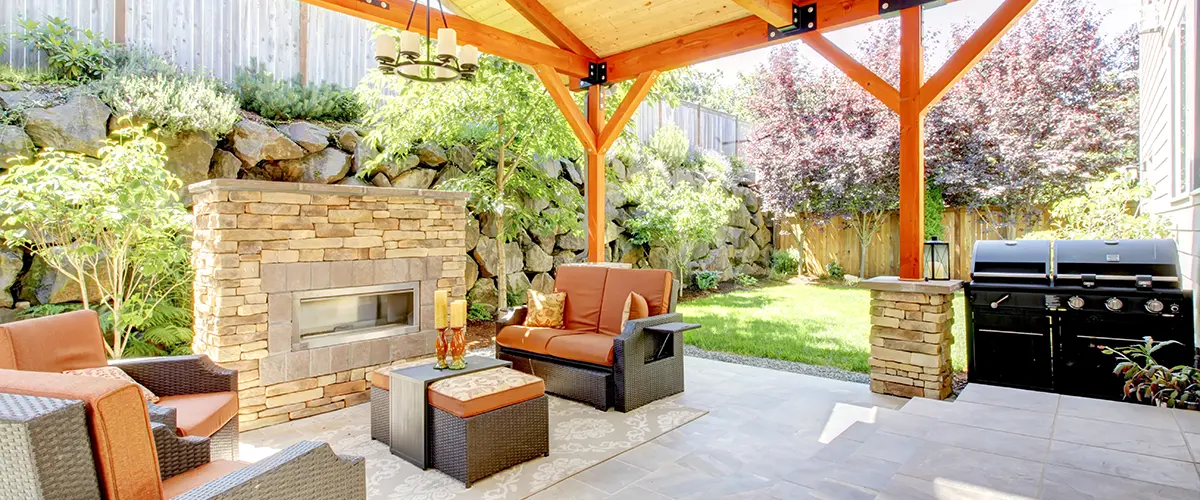 Elegant backyard patio featuring a wooden pergola, stone fireplace, and comfortable seating for outdoor living.