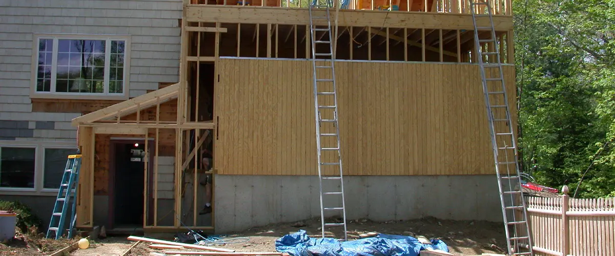 Home addition construction with exposed framing, ladders, and scaffolding showcasing an expansion project in progress.