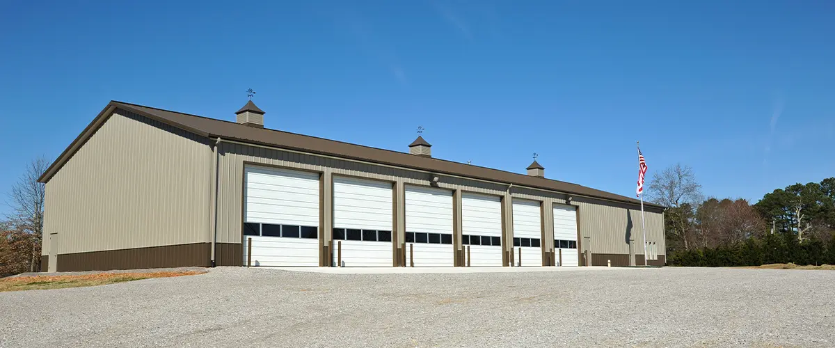 Large commercisl building with multiple garage doors under a clear sky.