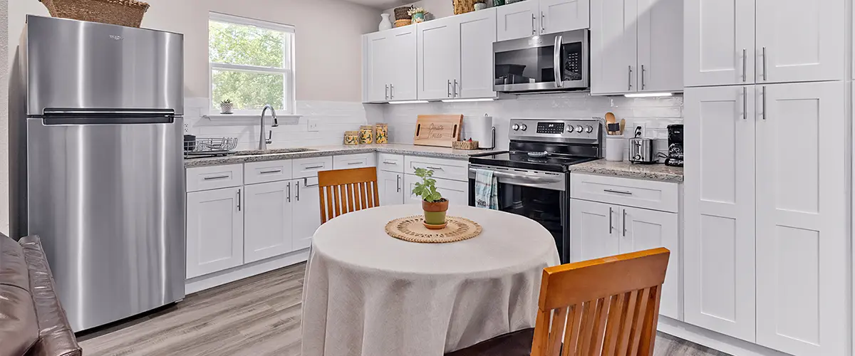 Modern kitchen with white cabinets, stainless steel appliances, and a cozy dining area, showcasing a stylish kitchen remodel.