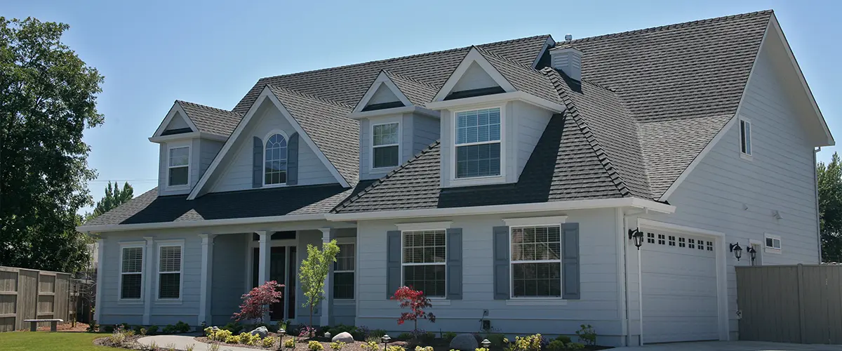 Modern suburban home with a newly installed asphalt shingle roof and white siding, showcasing exterior home improvement.