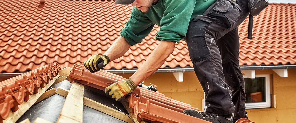 Professional roofer installing clay roof tiles on a residential home, ensuring durability and weather resistance.