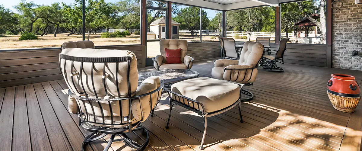 Screened-in deck porch with cozy outdoor seating, featuring a metal roof and scenic backyard views.