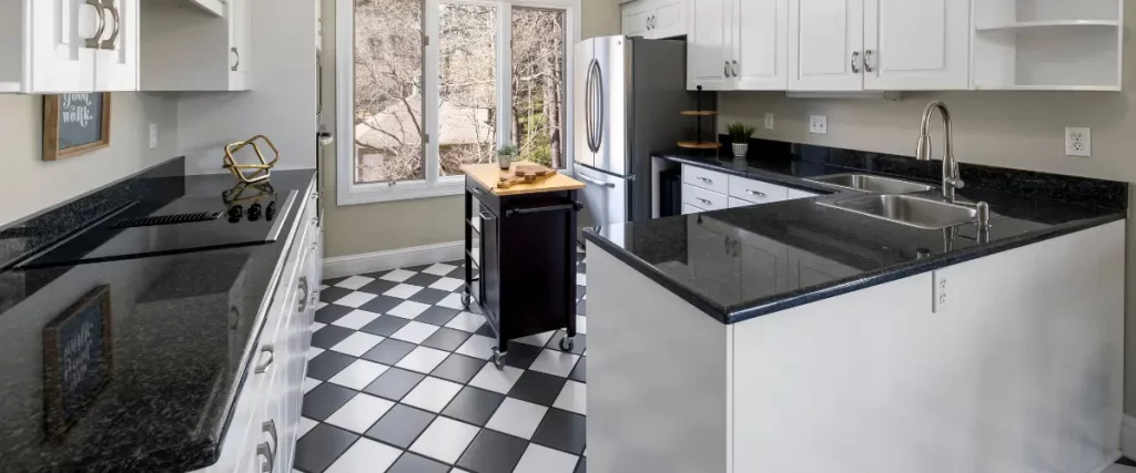 Modern kitchen with black granite countertops, white cabinetry, and a black and white checkered floor