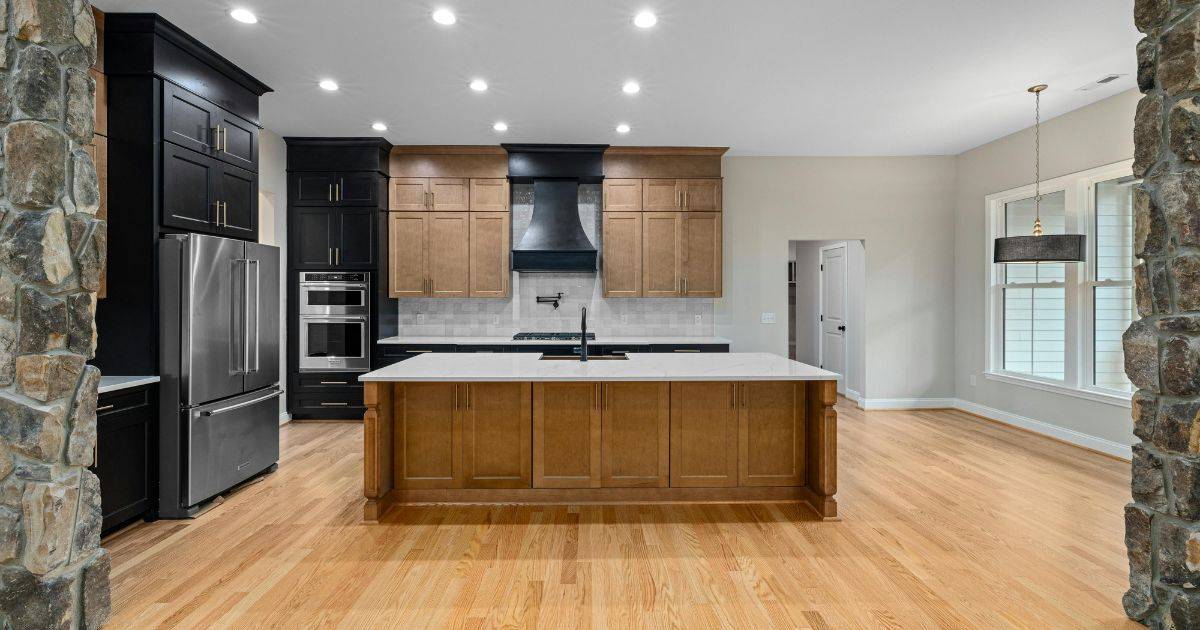 Modern kitchen with a large wood island, black and wood cabinetry, and stainless steel appliances