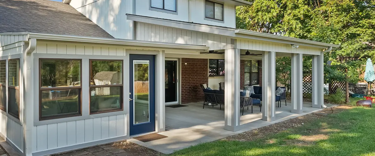 Backyard patio with covered porch and brick siding, featuring outdoor seating and a green lawn.