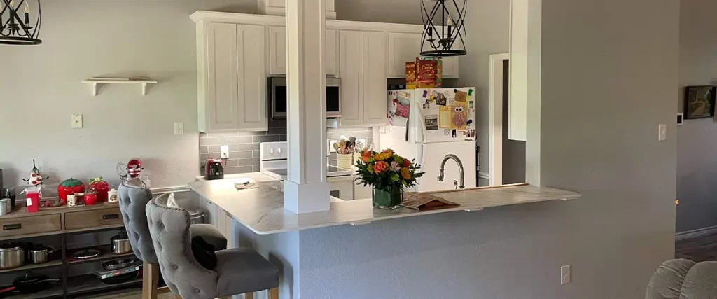 Contemporary open-concept kitchen with white cabinets, pendant lighting, and barstools. Perfect for home remodeling inspiration.