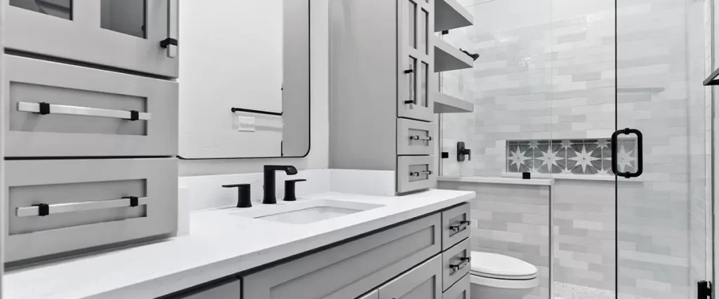 Elegant bathroom design with shaker cabinets, black fixtures, a glass-enclosed shower, and geometric tile flooring.