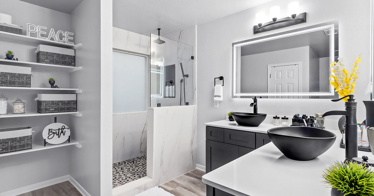 Elegant bathroom with a black vanity, vessel sinks, LED mirror, and a walk-in shower with marble tile.