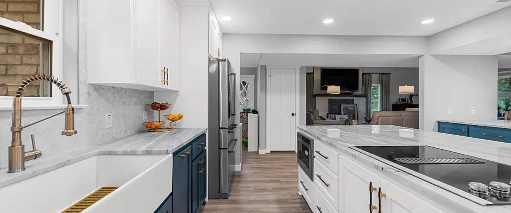 Elegant kitchen with blue lower cabinets, white uppers, marble countertops, and a farmhouse sink. High-end kitchen renovation ideas.