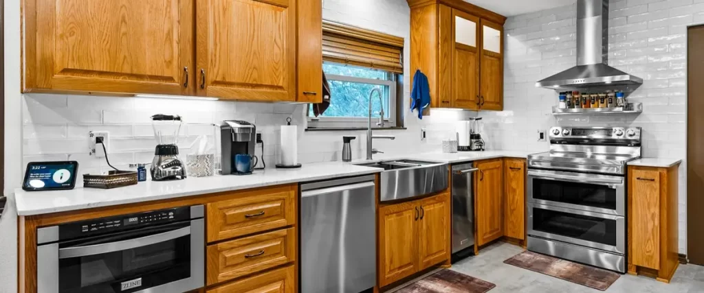 Renovated kitchen featuring oak cabinets, stainless steel appliances, farmhouse sink, and modern backsplash. Ideal for home upgrades.