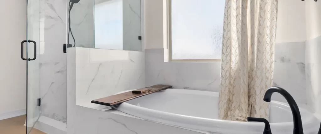 Spacious modern bathroom featuring a freestanding tub, glass shower, and marble tile walls.