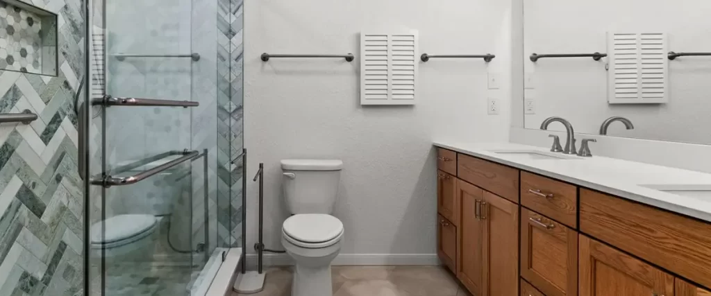 Stylish bathroom featuring a wood vanity, subway tile, and a glass shower with herringbone tile.