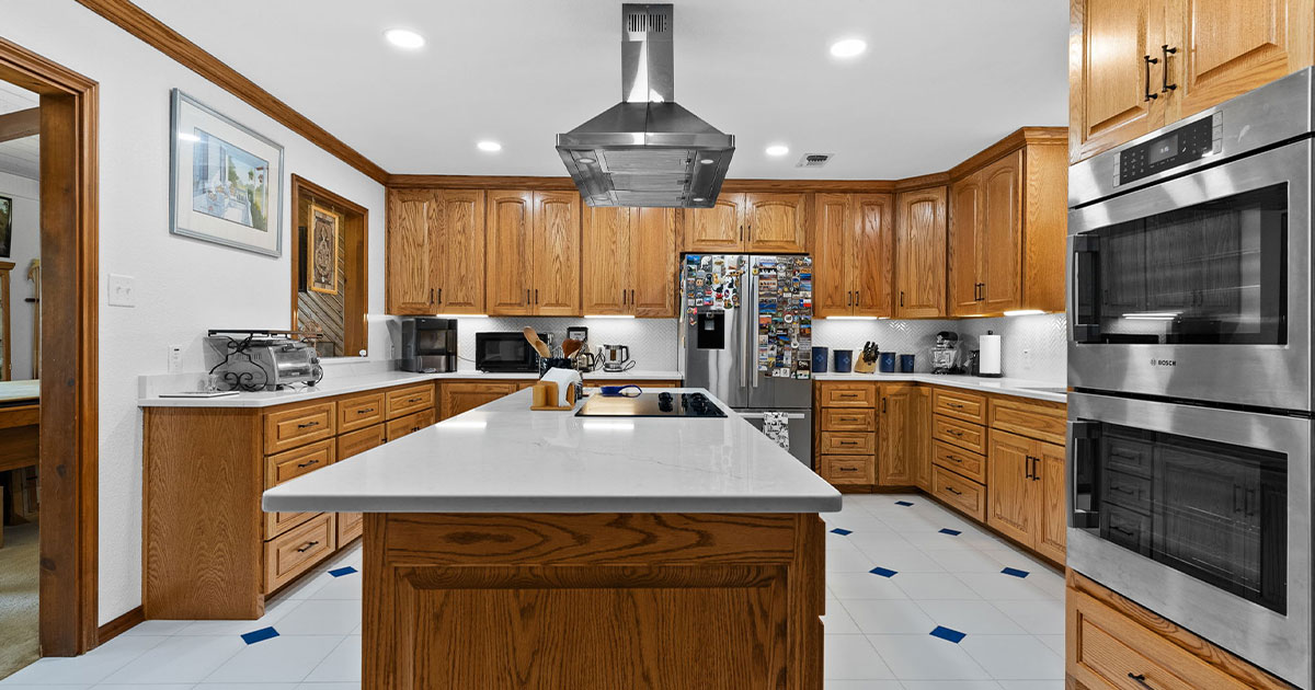 Traditional kitchen with wooden cabinets, white quartz countertops, and stainless steel appliances for a warm, rustic look.