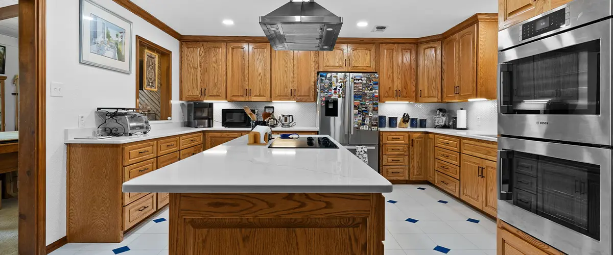 Traditional kitchen with wooden cabinets, white quartz countertops, and stainless steel appliances for a warm, rustic look.