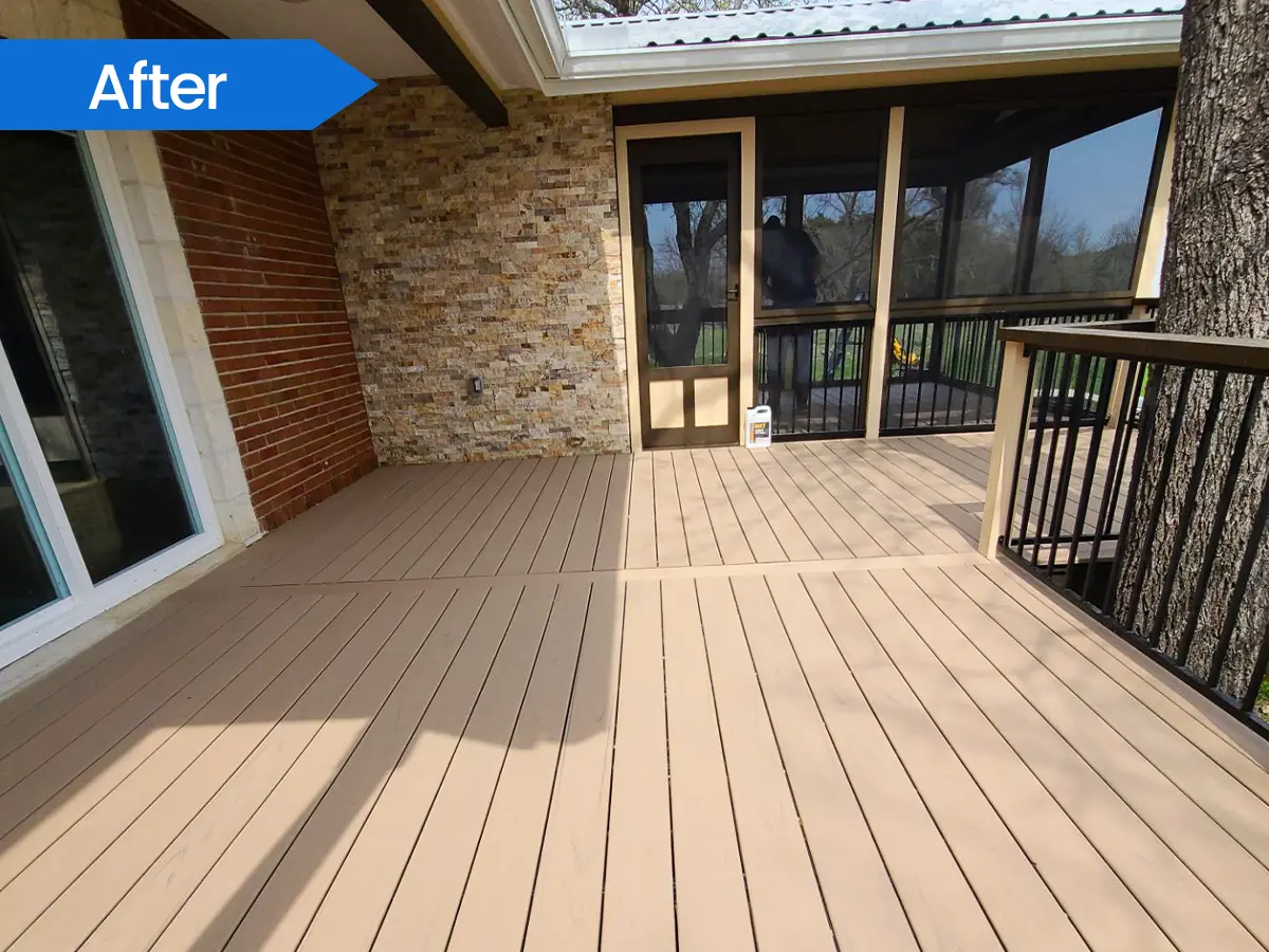 Spacious backyard deck with composite flooring, stone walls, and glass doors leading inside.