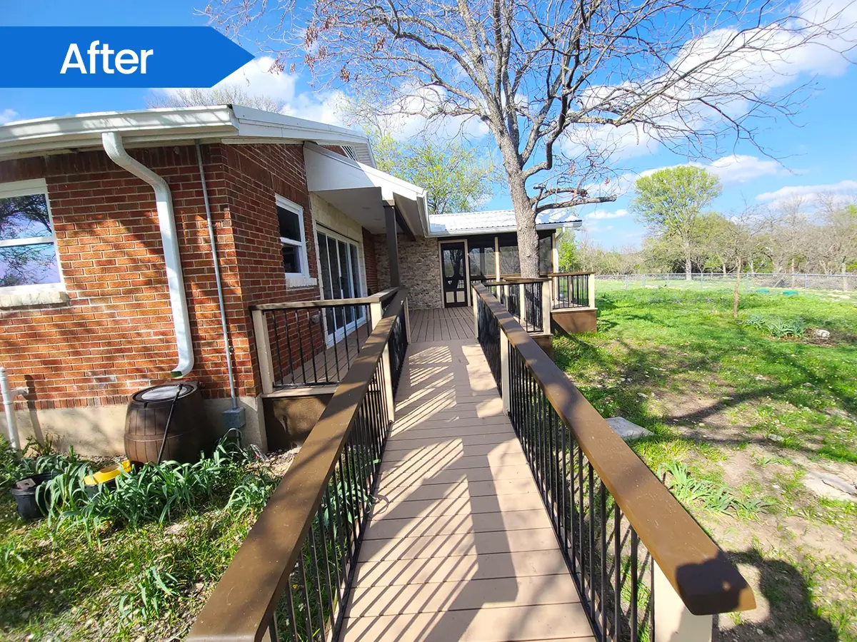 Wooden accessibility ramp with black metal railings leading to a back deck.