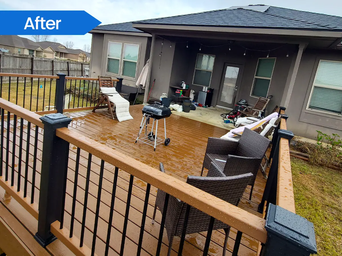 Wet wooden deck with outdoor seating and black railings attached to a modern home.