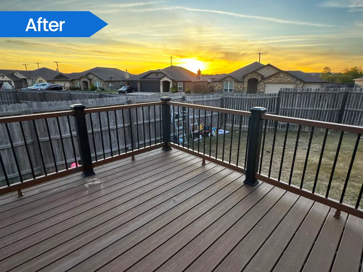 Composite deck with black railings offering a scenic sunset view over suburban rooftops.