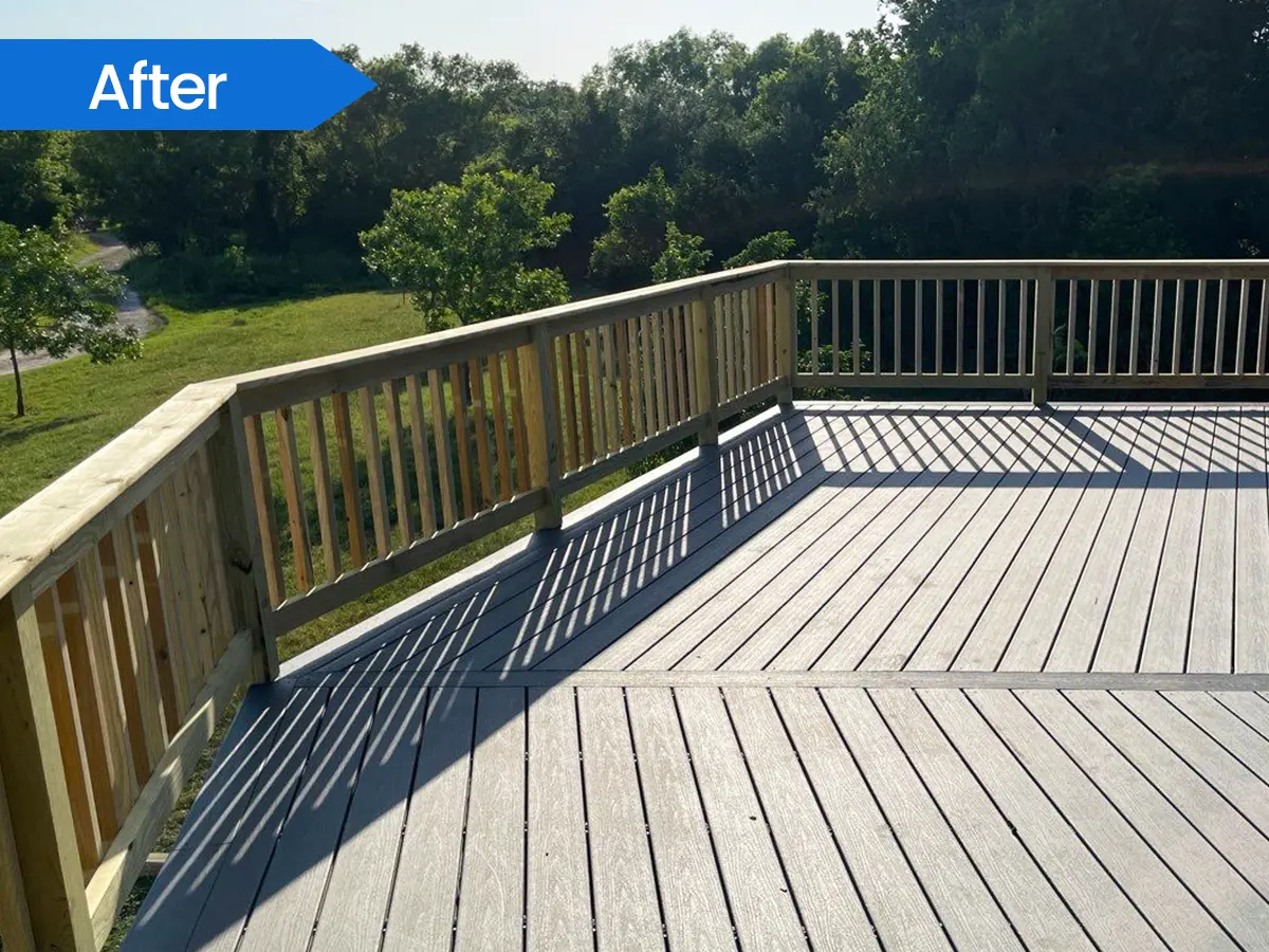 Spacious composite deck with wooden railings overlooking a scenic backyard.