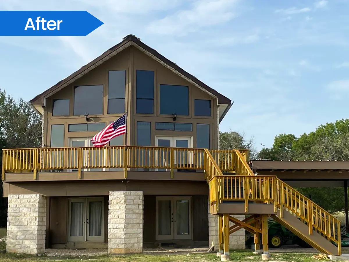 Modern A-frame home with a large elevated wooden deck and American flag.