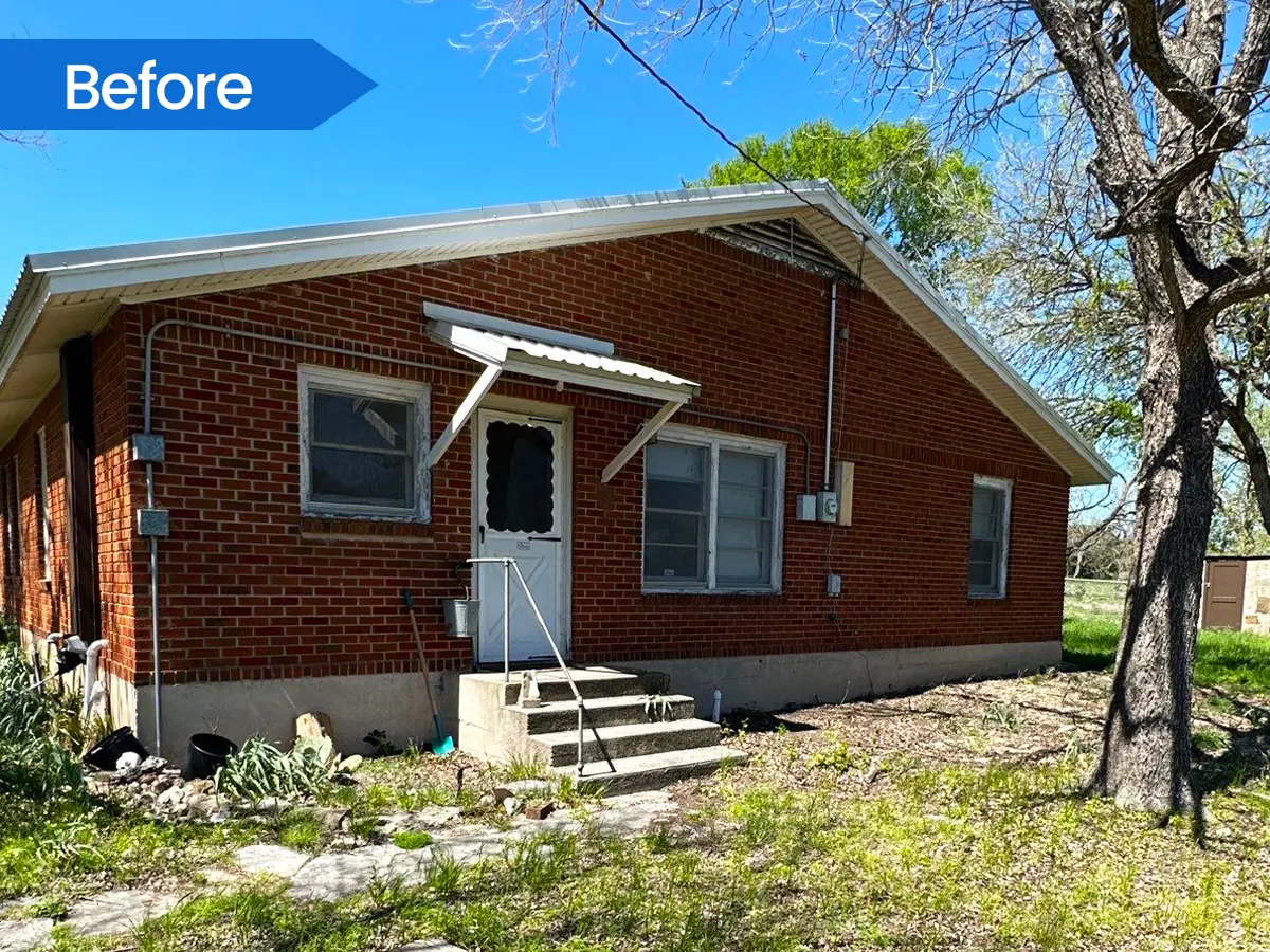 Brick home with a front porch and steps, surrounded by trees and a natural yard before deck building.