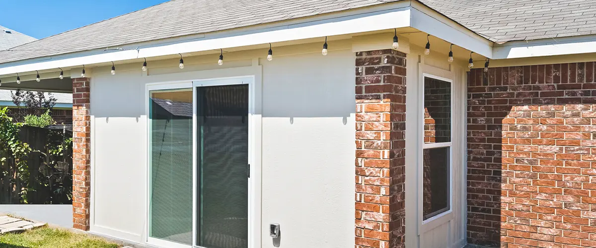 Brick and siding house exterior with new sliding glass door and backyard patio renovation