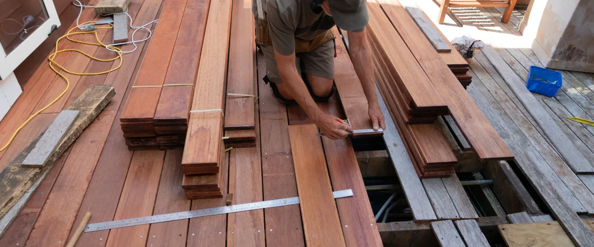 Contractor measuring wood planks for new deck construction