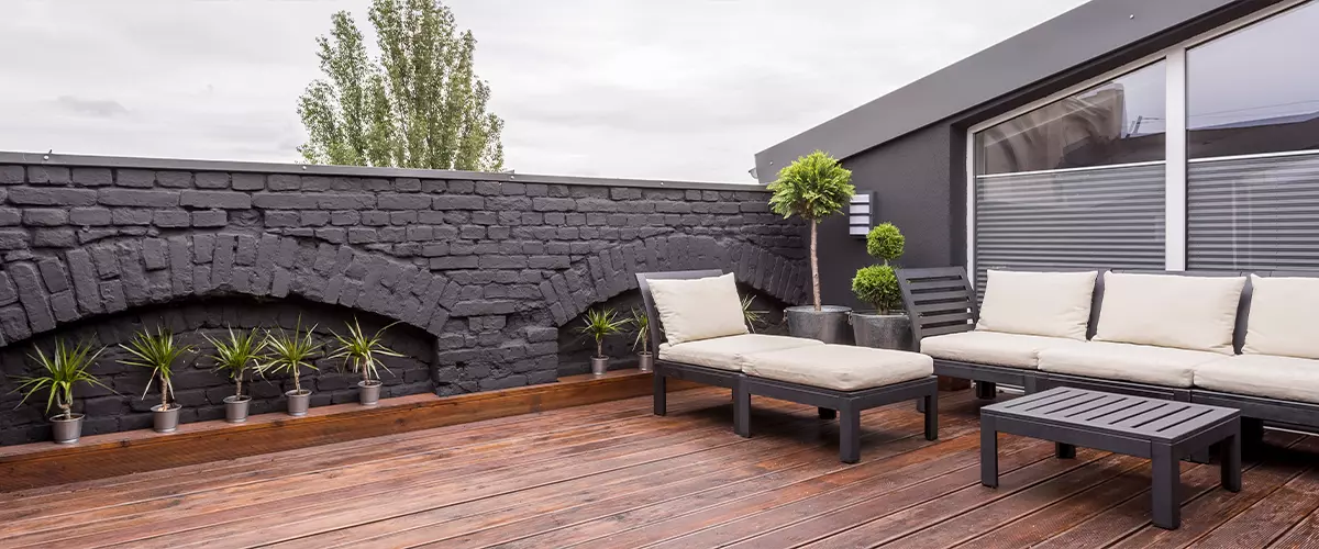 Rooftop deck with black brick wall and cushioned lounge seating
