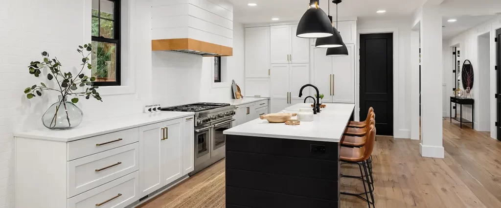 Modern white kitchen with black island and pendant lights