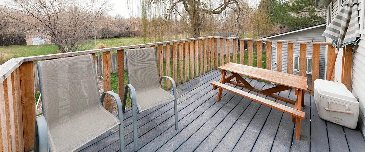 Small backyard deck with wood railing and seating