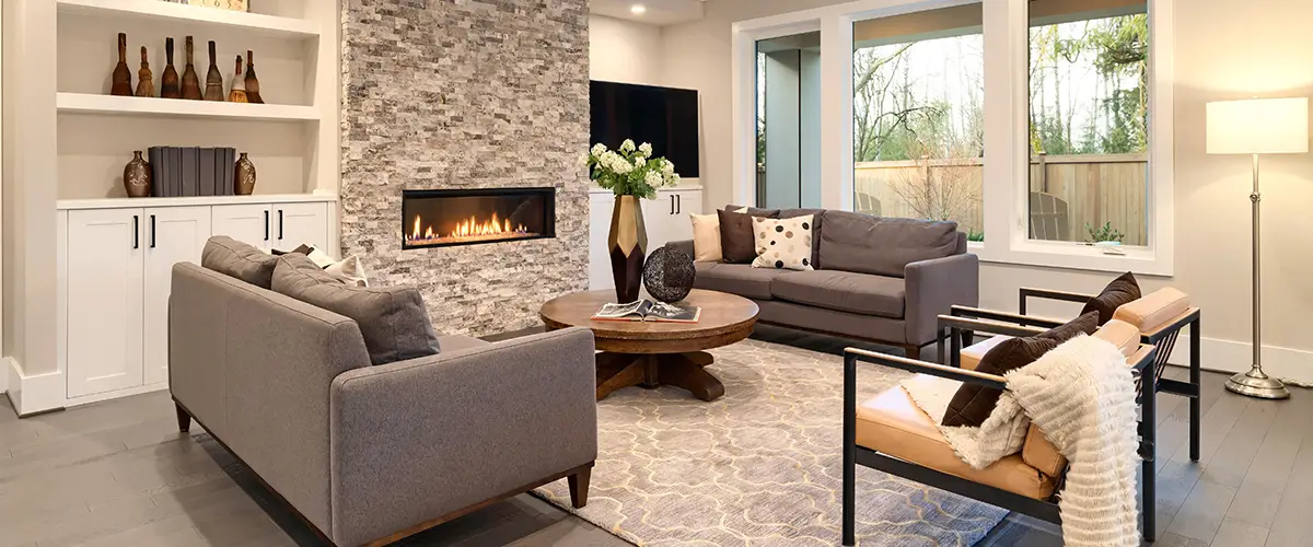 Modern living room with gray sofas, stone fireplace, and built-in shelves