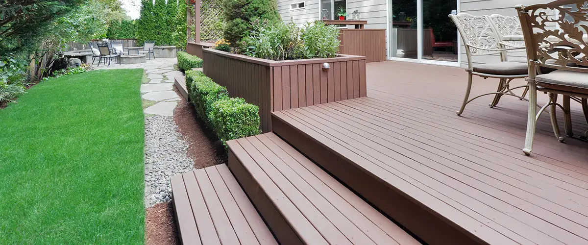Elevated brown deck with steps and garden landscaping