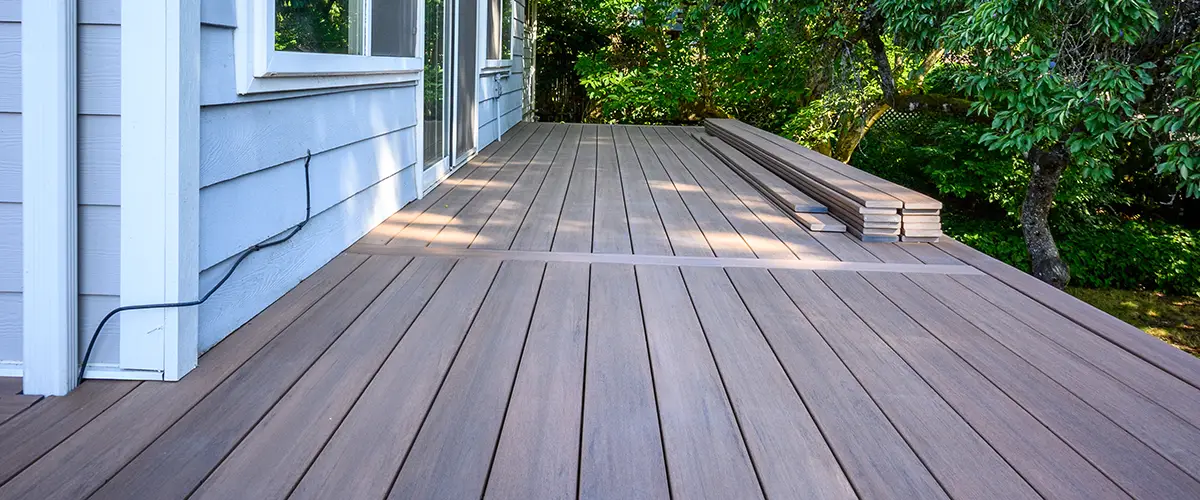 Modern composite deck with clElevated brown deck with steps and garden landscapingean finish