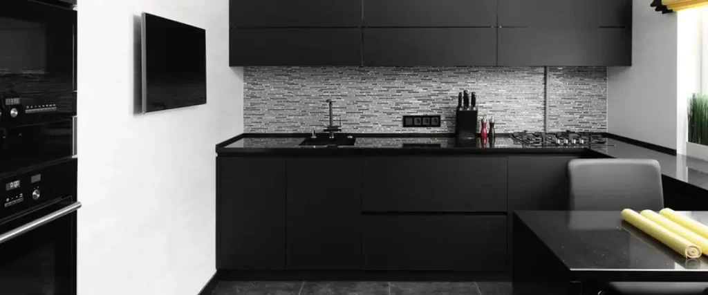 A sleek, minimalist black kitchen with handleless cabinets, a dark tile backsplash, and black granite countertops.