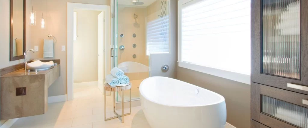 A bright, contemporary bathroom featuring a white freestanding oval tub and a large, multi-jet glass walk-in shower with a rainfall showerhead.