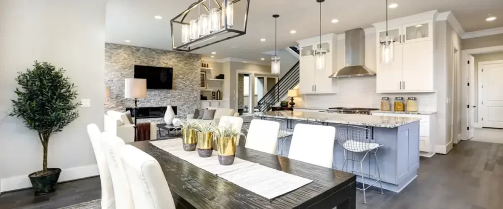 Elegant dining and kitchen space with pendant lights, marble countertops, and wood flooring.