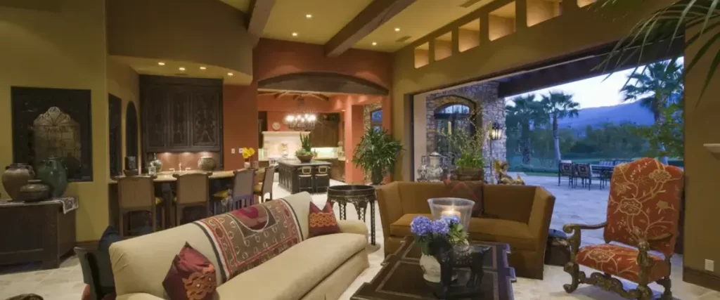 Warm Mediterranean-style living room with rustic beams, rich colors, and open patio access.