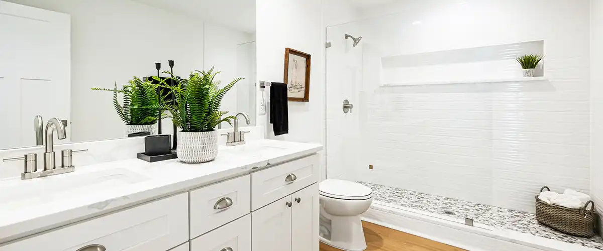 White shower remodel with glass shower and double sink vanity