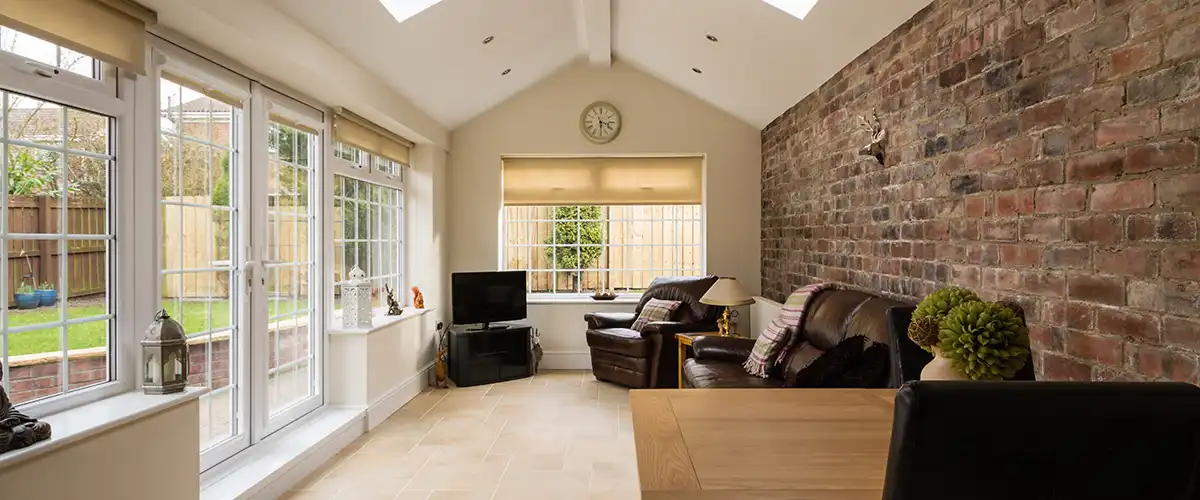 Bright sunroom addition with large windows and brick accent wall