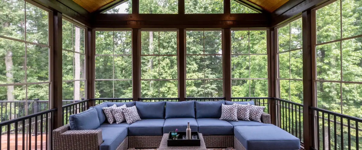 a screened porch featuring a large blue sectional sofa and a coffee table