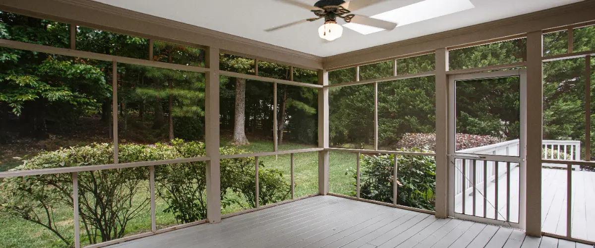 a screened porch with a composite deck floor and a door leading to an open deck area
