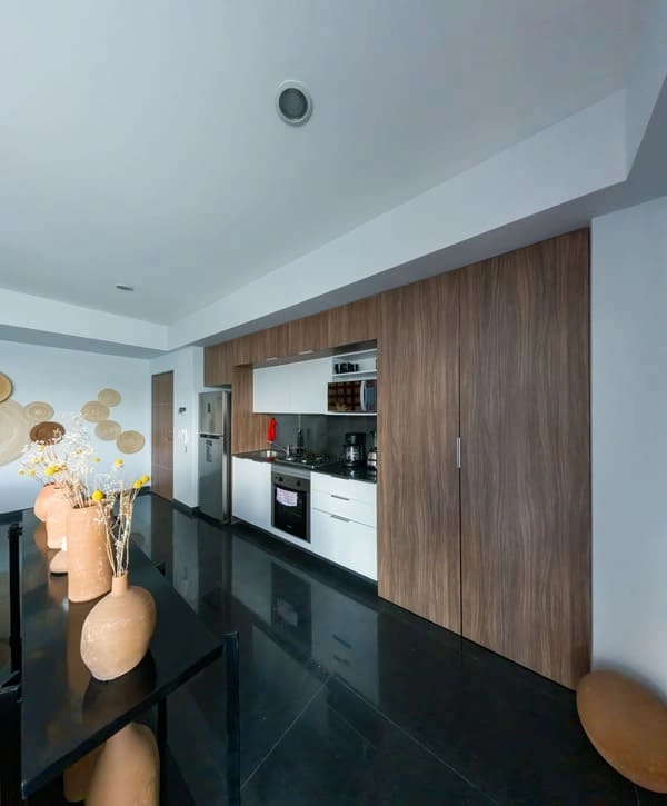 A sleek, compact kitchen area with dark floors and wood cabinetry inside a professional garage conversion in Bell County, TX.