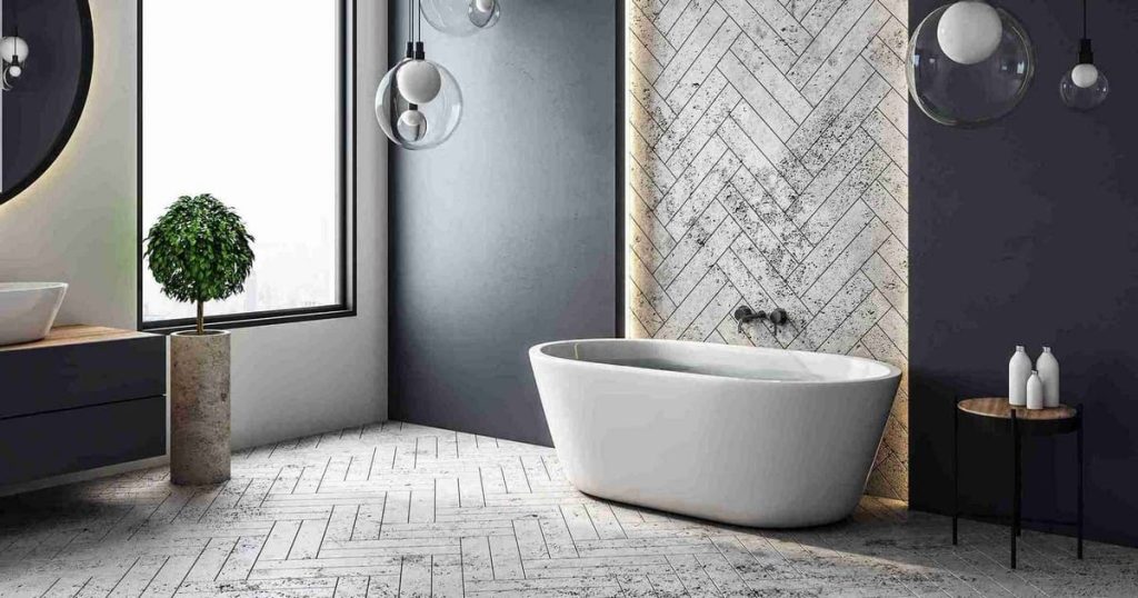 A luxury bathroom conversion ideas inspiration featuring a freestanding white soaking tub against a herringbone tiled accent wall with ambient pendant lighting.