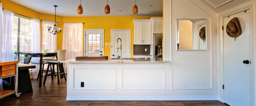 Spacious interior showing a bright kitchen with a breakfast bar and dining table in an open concept layout.
