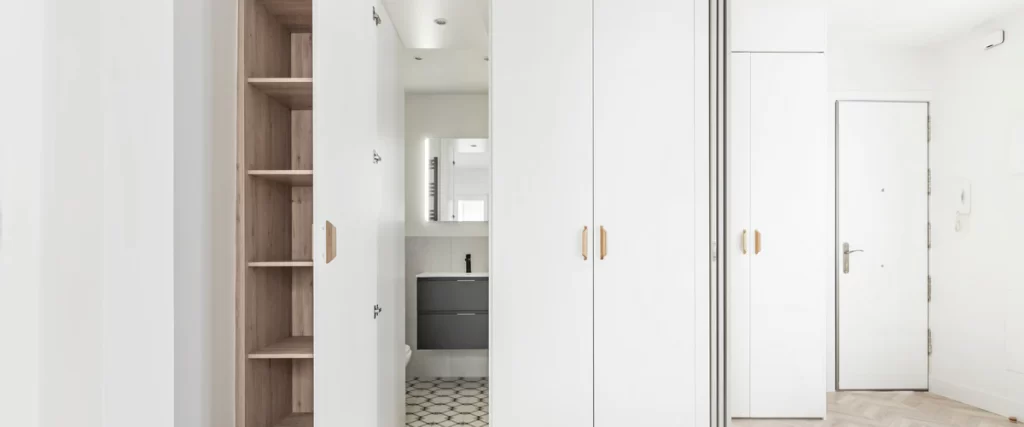 Sleek white built-in hallway closets with wooden shelving units designed for maximum home storage.