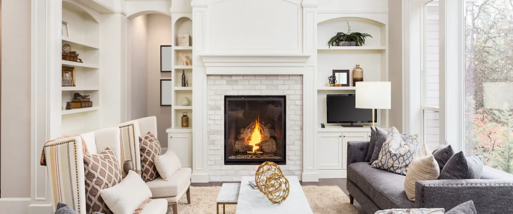 Elegant living room with custom white built-ins flanking a brick fireplace with a burning fire and neutral decor.