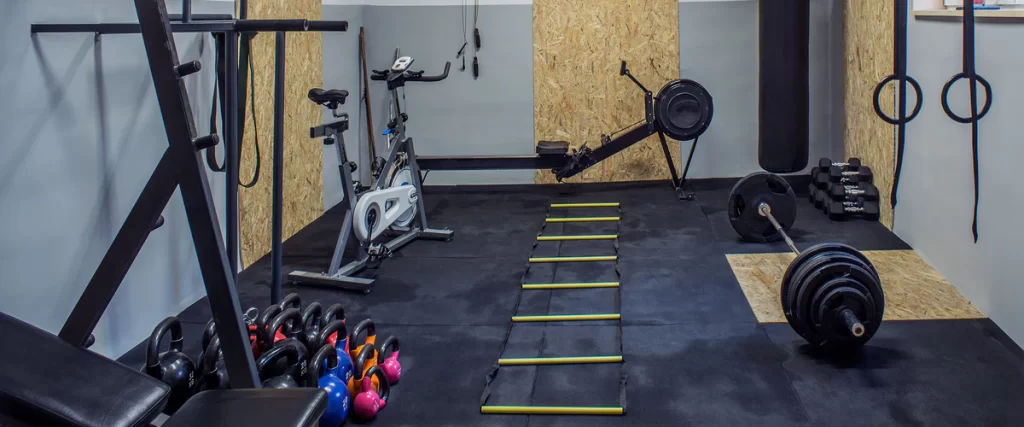 Functional home gym garage conversion with rubber flooring, stationary bike, rowing machine, and kettlebells.