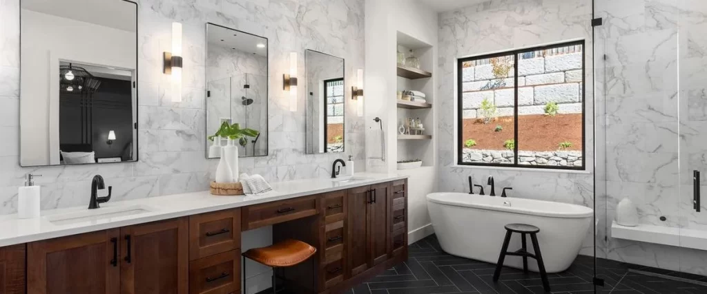 A contemporary bathroom with white marble wall tiles, a dark wood double vanity, and a freestanding white soaking tub.