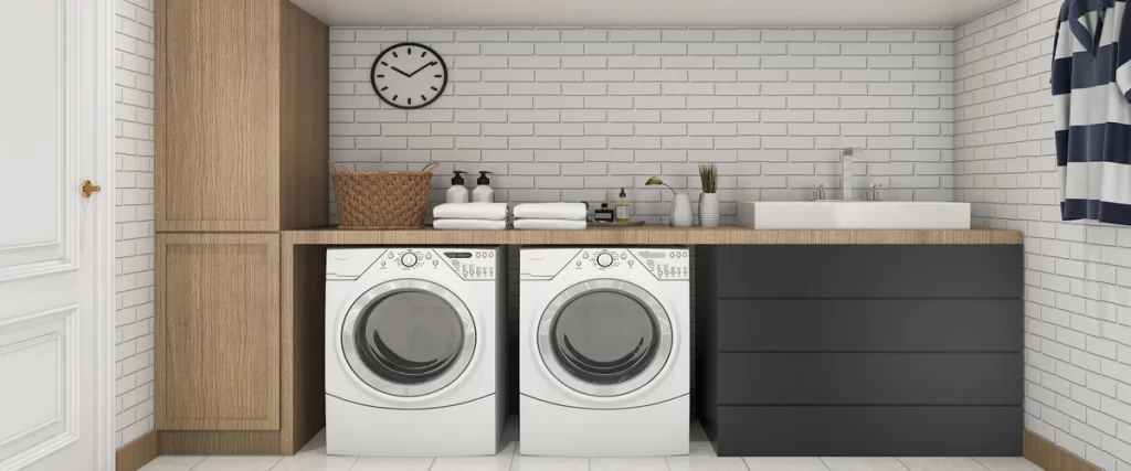 A clean, modern laundry room with white front-load appliances, a wooden countertop, and a white brick backsplash.